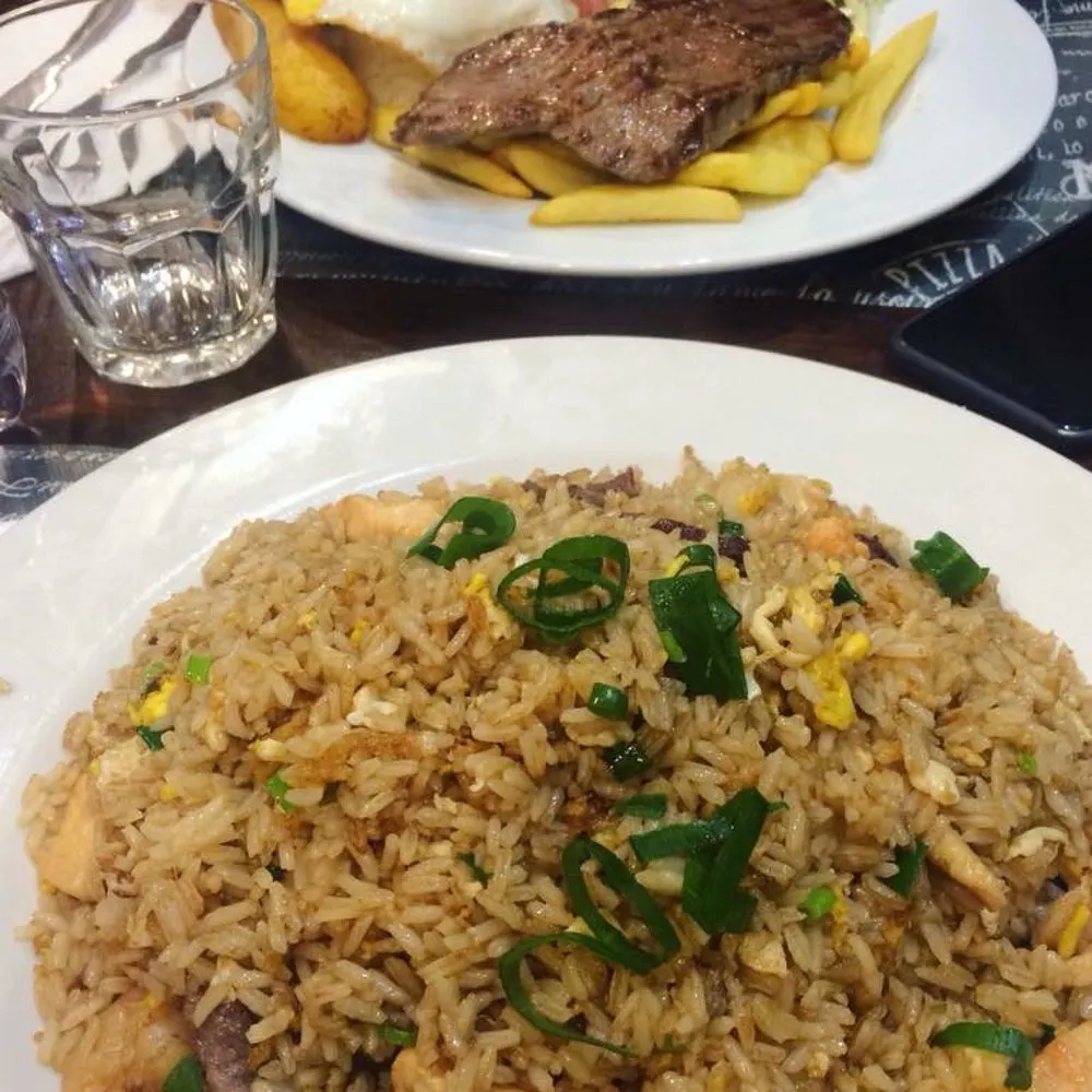 Arroz chaufa fumante con bistec a lo pobre sullo sfondo