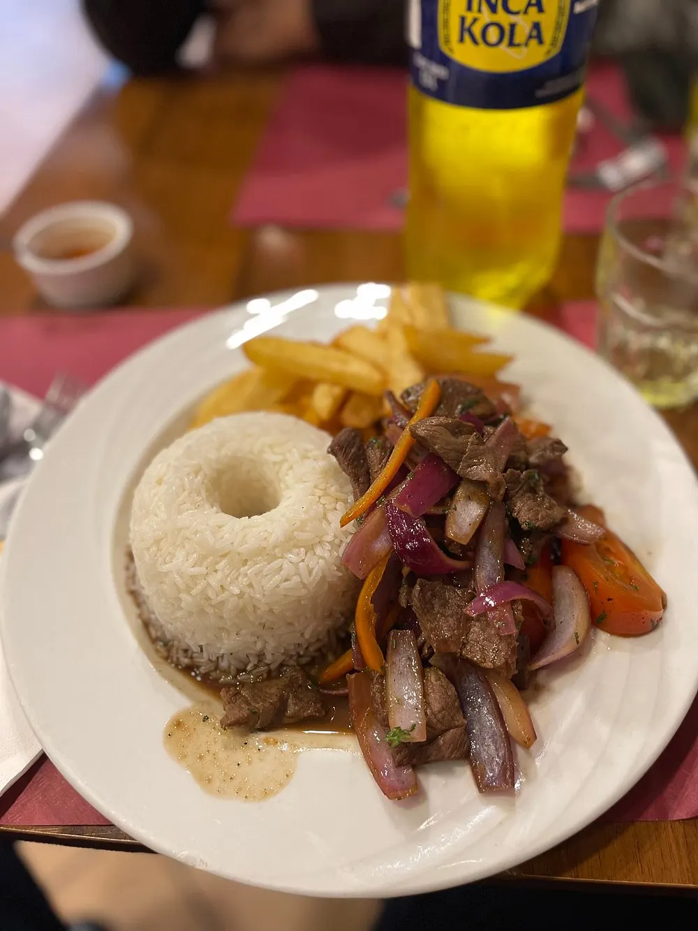 Lomo saltado con riso e patate fritte, accanto a una Inca Kola